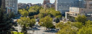 Vue aérienne d'une avenue urbaine bordée d'arbres, entre bâtiments résidentiels et de bureaux